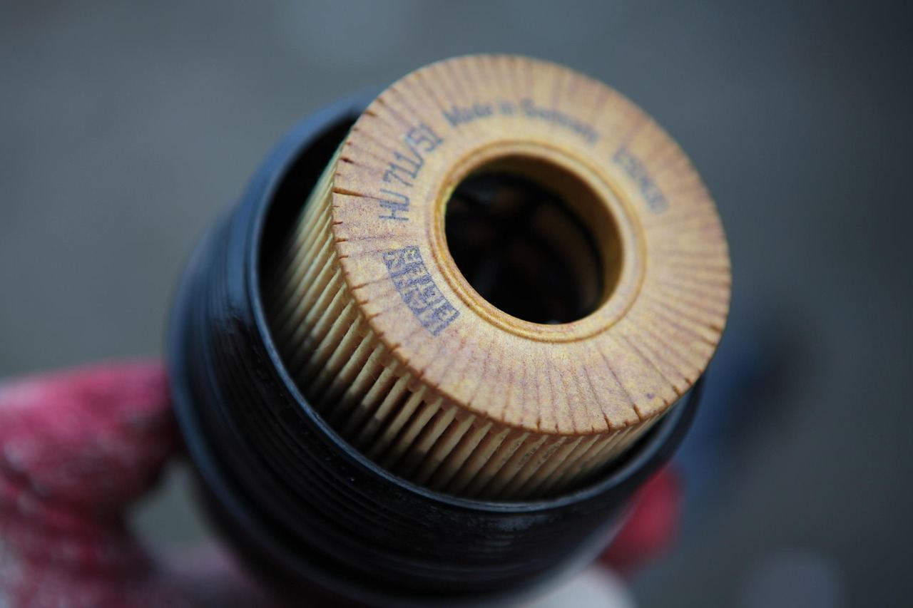 A worker in a bucket hat repairs an outdoor air conditioning unit on a rooftop.