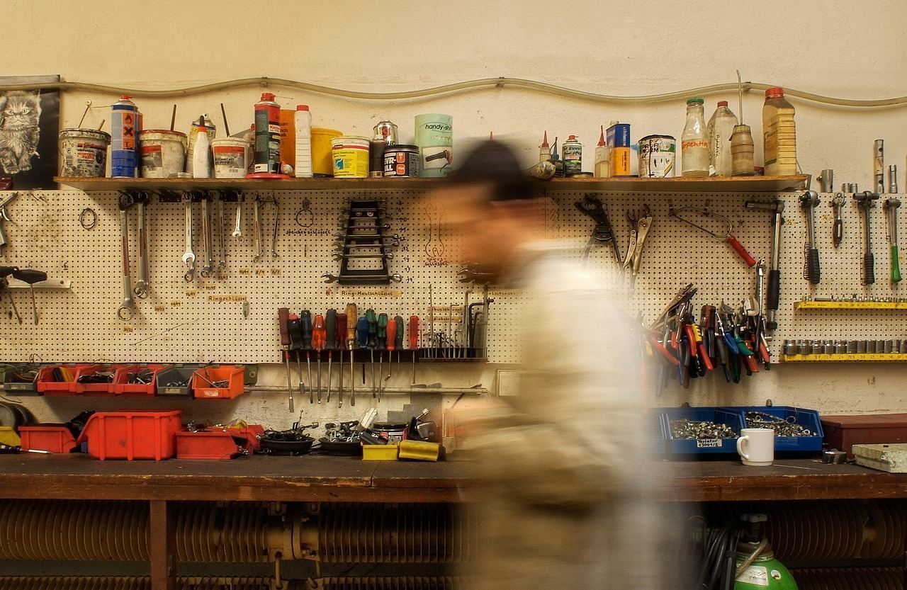Close-up of a technician working on an air conditioning unit with tools on a sunny day.