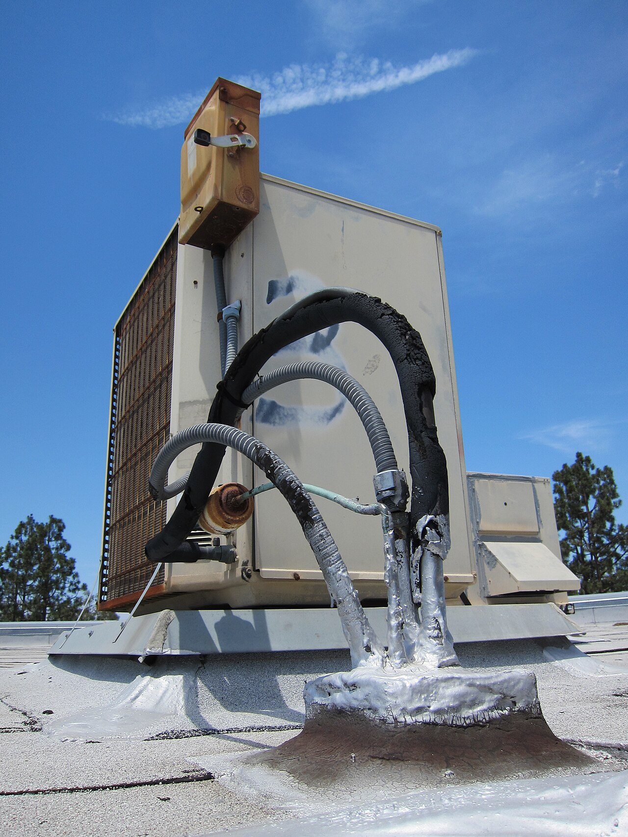 Aging rooftop condenser unit of a split air conditioning system with weathered, rusted components